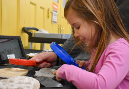 girl looking at fossils with magnifying glass