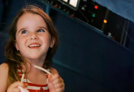 A child smiles in front of a navy blue background