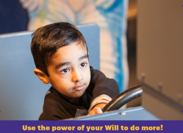 A boy in black t-shirt holding on to a steering-wheel replica