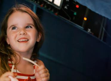 A child smiles in front of a navy blue background