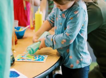 girl with ribbons paints with squeeze bottle