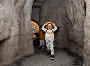 Child runs through cave exhibit with a hard hat on